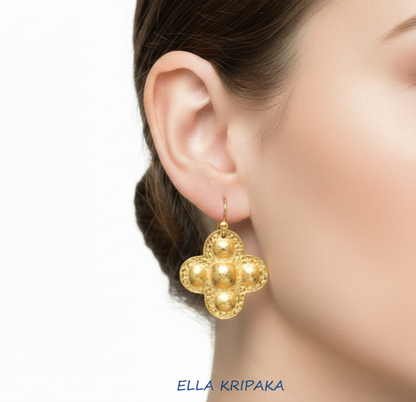 24k 9999 gold hammered Byzantine Cross earring with forged gold textures is worn by person , artist's name 'Ella Kripaka'