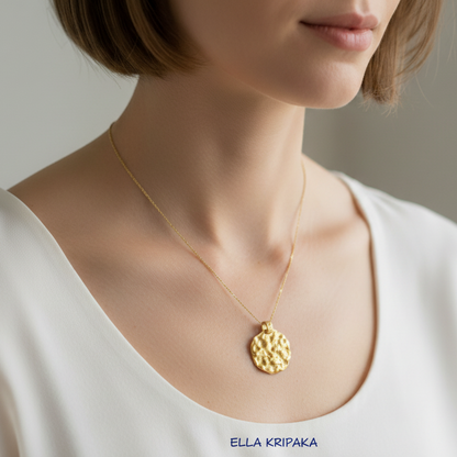 Organic 24k 9999 gold hammered uneven disk on chain wearing on woman in a white t-shirt, branded 'Ella Kripaka'