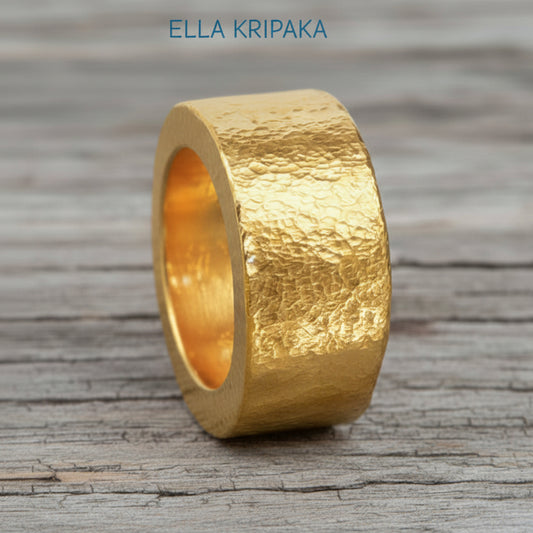 Hammered 24k Gold 9999 gold ring thick heavy and with textured surface on a grey wooden background, branded 'Ella Kripaka'