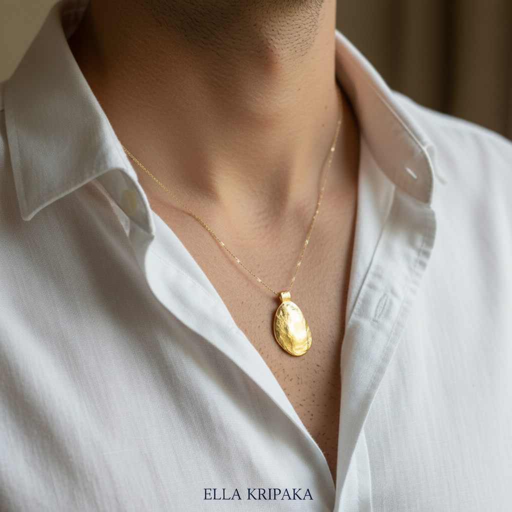 Organic 24k gold convex uneven oval pendant with hammered textures is worn by a man with white shirt and on neutral background, branding artist 'Ella Kripaka'