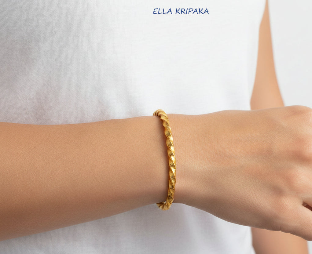 Viking Twisted Hammered 24k 9999 gold cuff thick bracelet worn on a wrist by a woman on a white background, artist-jeweler name 'Ella Kripaka' branding