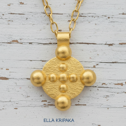 24k 9999 gold hammered disk pendant with 9 convex rounds and with forged gold textures is on white old woiden surface, artist's name 'Ella Kripaka'