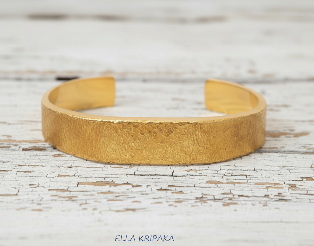 Hammered 24k 9999 Gold thick cuff bracelet Ancient Rome style on a ehote old wooden background with 'Ella Kripaka' branding