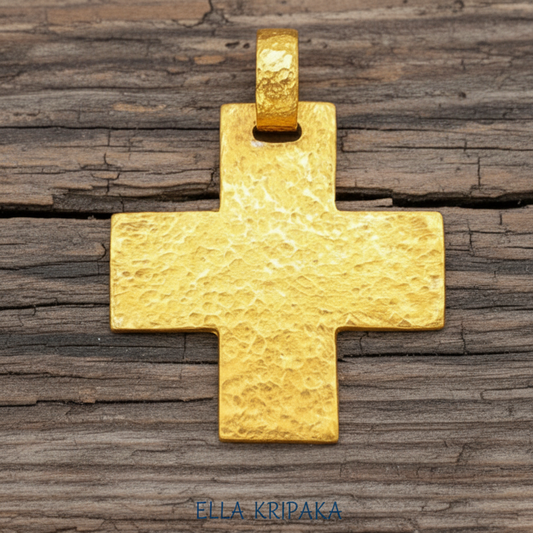 Hammered 24k 9999 gold textured cross pendant on rustic wooden surface, branding artist name 'Ella Kripaka'