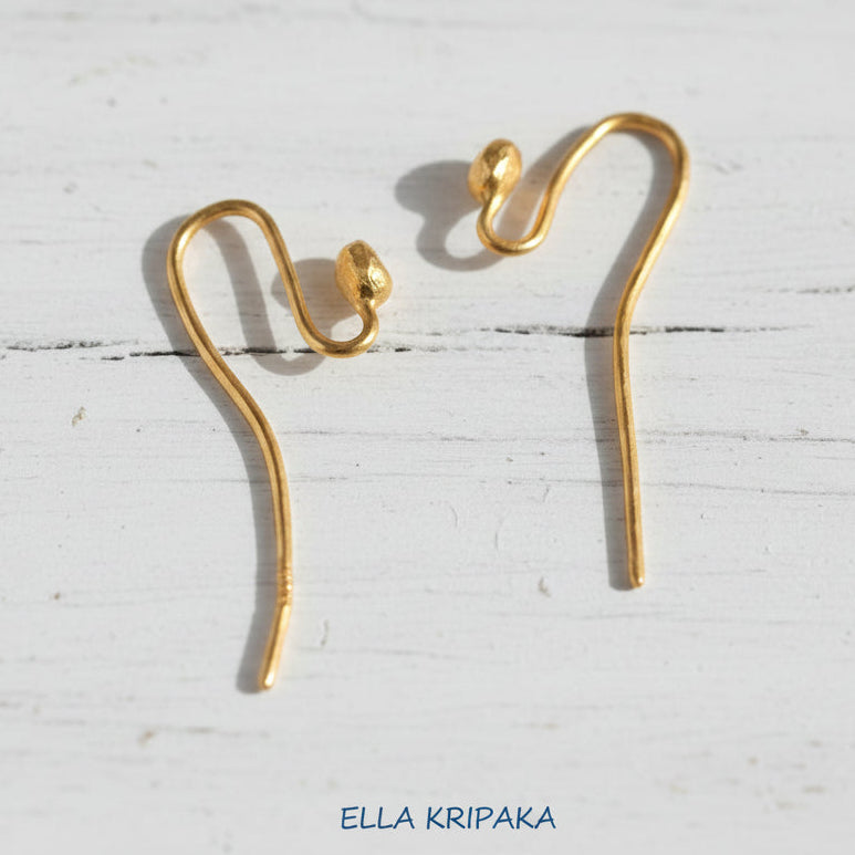 22k gold earring hooks clasps on a white wooden surface with 'Ella Kripaka' branding