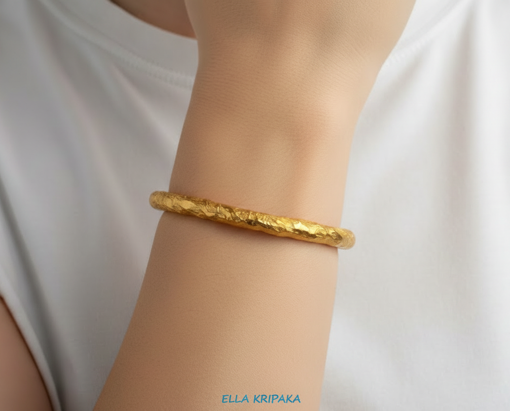 Organic hammered 24k 9999 gold bracelet uneven cuff worn on wrist by a person and on a white background, branding artist-jeweler name 'Ella Kripaka'