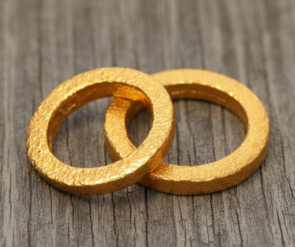 Hammered 24k Gold 9999 gold Ancient Rome  thick two rings with textured forged gold on a grey old wooden background, branded artist-jeweler's name 'Ella Kripaka'