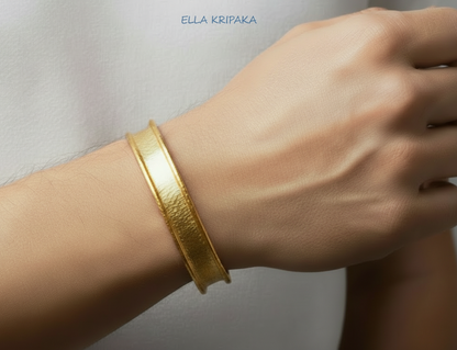 Hammered 24k 9999 gold bracelet cuff with thuck borders is worn on a man's wrist and on white blurred background, branding artist-jeweler name 'Ella Kripaka'