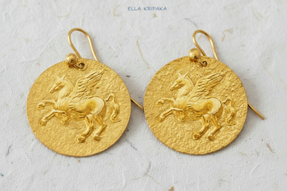 Hammered 24k Gold 9999 gold disk earrings with convex Pegasus and with forged textured gold on white craft paper background, branded artist's name 'Ella Kripaka' 