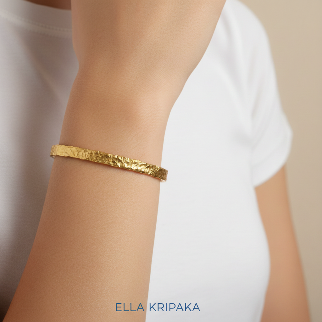 Organic hammered 24k 9999 gold bracelet uneven cuff worn on a person's wrist and on a white background, branding artist-jeweler name 'Ella Kripaka'
