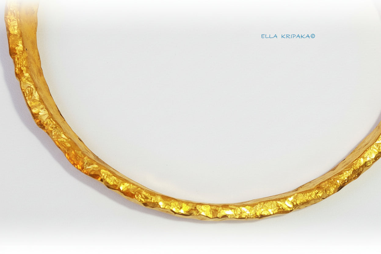 Organic hammered 24k gold bracelet cuff with uneven edges is on light surface, branding artist's name 'Ella Kripaka'
