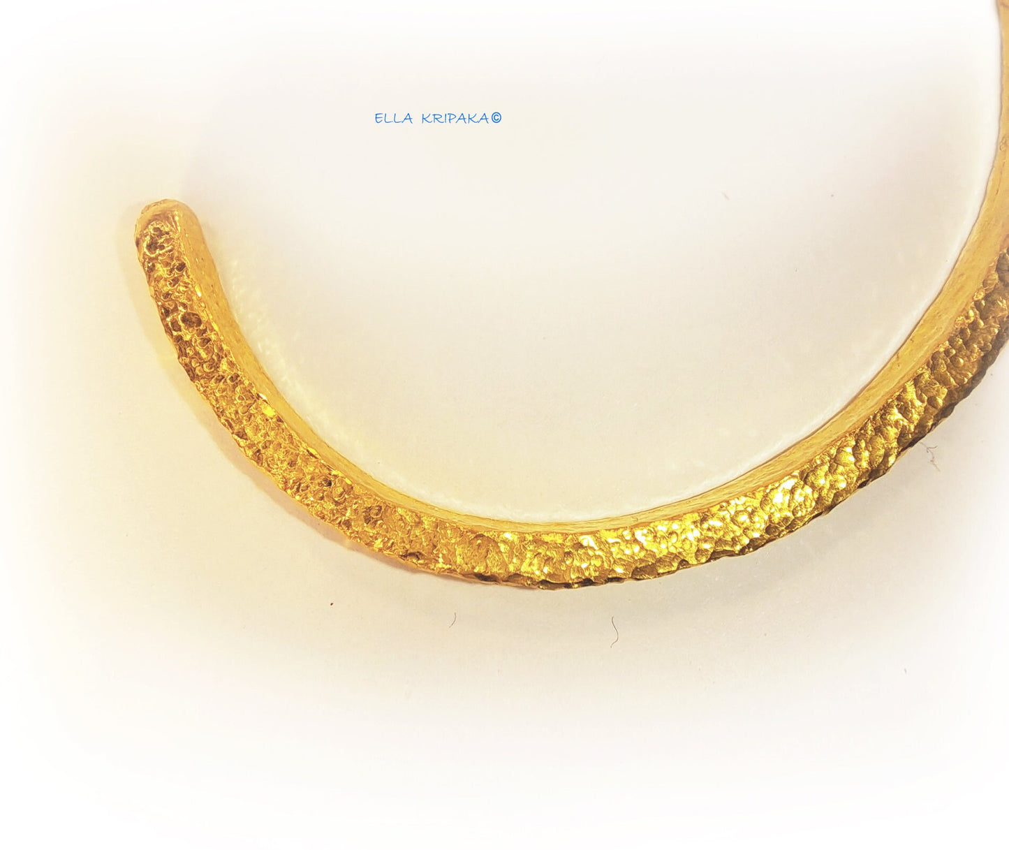 Hammered 24k 9999 gold cuff thick bracelet Ancient Rome style on a white background, artist-jeweler name 'Ella Kripaka' branding