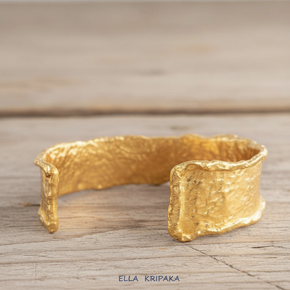 Organic hammered 24k gold bracelet cuff wifh folded uneven edges on a rustic wooden background, branding artist 'Ella Kripaka'