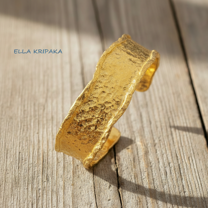 Organic hammered 24k 9999 gold bracelet uneven cuff on a old white wooden background, branding artist-jeweler name 'Ella Kripaka'