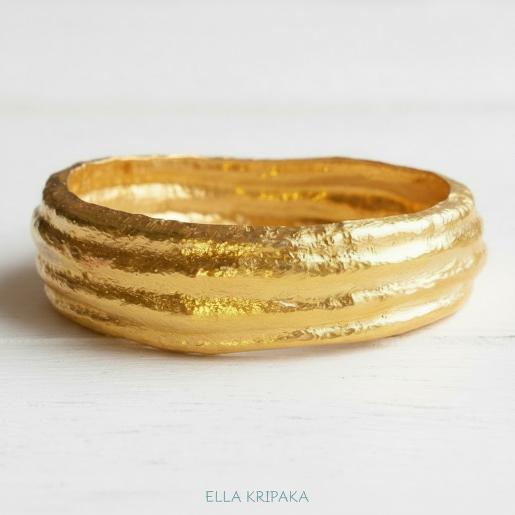 Organic 24k 9999 Gold hammered uneven bangle bracelet is on white surface, artist's name 'Ella Kripaka' branding