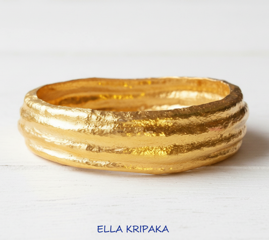 Organic 24k 9999 Gold hammered uneven bangle bracelet is on white surface, artist's name 'Ella Kripaka' branding