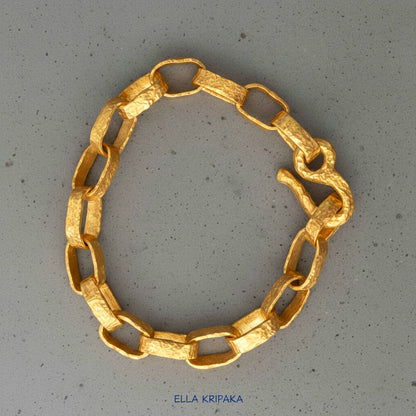Hammered 24k 9999 gold chain thick bracelet with thick hook clasp Ancient Rome style on a grey background, artist-jeweler name 'Ella Kripaka' branding