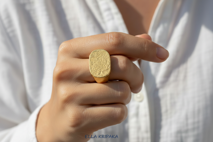 Hammered 24k 9999 Gold ring thick signet Ancient Egypt style and Ancient Rome style and with forged textured gold worn on model's finger and on a white plain background, artist-jeweler's name 'Ella Kripaka' branding