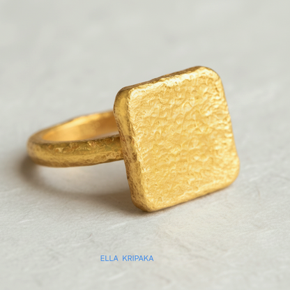 Hammered 24k 9999 Gold thick ring square signet Ancient Rome style with a textured forged gold surface on a white craft paper background, branded 'Ella Kripaka'
