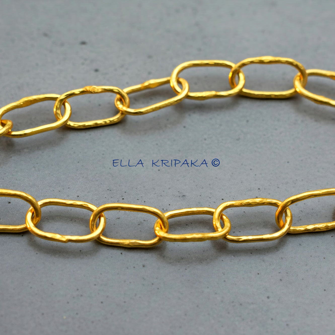 22k gold hammered chain on grey concrete background, artist-jeweler's name 'Ella Kripaka' branding