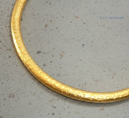 Hammered 24k 9999 gold cuff thick bracelet Ancient Rome style with shiny forged textures is on a grey background, artist-jeweler name 'Ella Kripaka' branding