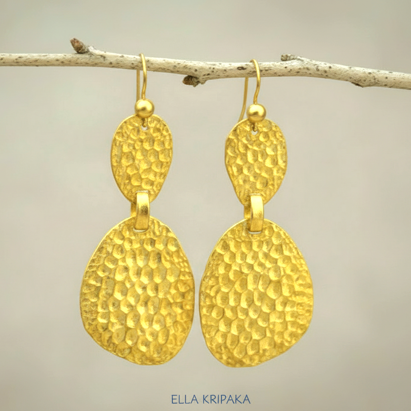 Organic 24k 9999 gold hammered uneven earrings with shiny gold textures are hanging on thin branch on on neutral background, artist-jeweler's name 'Ella Kripaka'