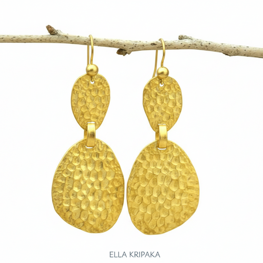 Organic 24k 9999 gold hammered uneven earrings with shiny gold textures are hanging on thin branch on on white background, artist-jeweler's name 'Ella Kripaka'