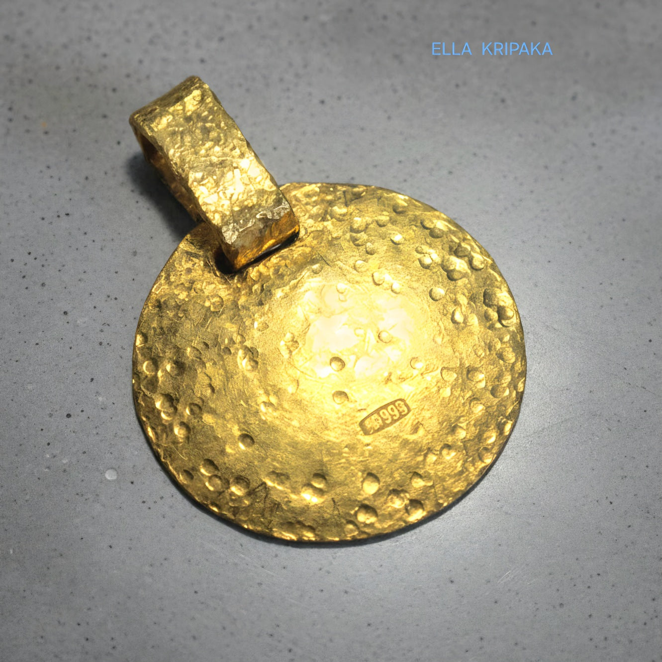 Hammered 24k gold, pure 9999 gold disk pendant with shiny forged gold textures on grey concrete surface, artist-jeweler 'Ella Kripaka' branding