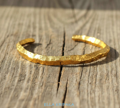 Organic hammered 24k 9999 Gold thick uneven cuff bracelet on a wooden background with 'Ella Kripaka' branding