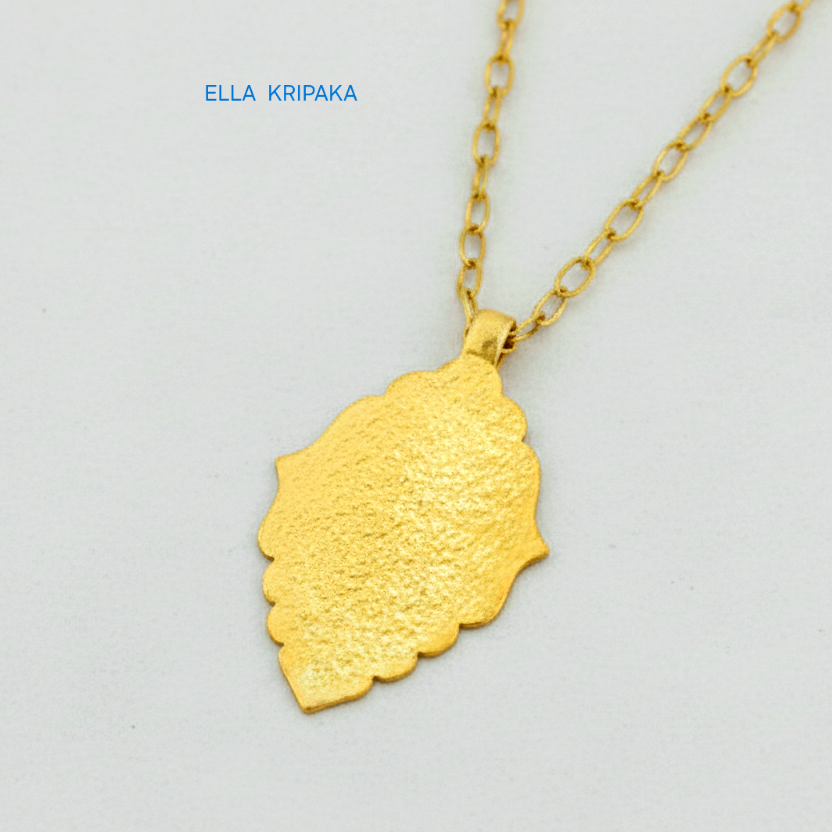 Hammered 24k gold Byzantine ornament pendant with chain on a white surface with 'Ella Kripaka' branding