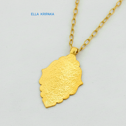 Hammered 24k gold Byzantine ornament pendant with chain on a white surface with 'Ella Kripaka' branding