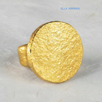 Hammered 24k 9999 Gold thick ring disk signet Ancient Rome style and Byzantine style with a textured gold on a white craft paper background, branded 'Ella Kripaka'