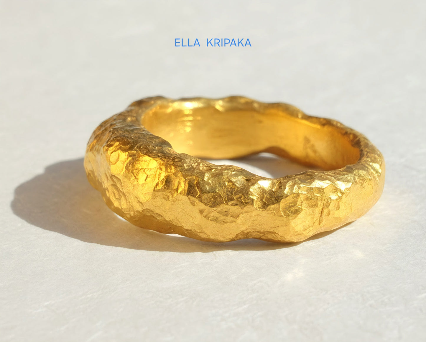 Hammered twisted 24k Gold 9999 gold signet thick ring Ancient Rome style with textured gold on white old wooden background, branded 'Ella Kripaka'