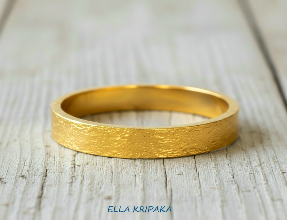 Hammered 24k Gold thick bangle bracelet with gold textures on light grey old wooden surface, artist's name 'Ella Kripaka' branding