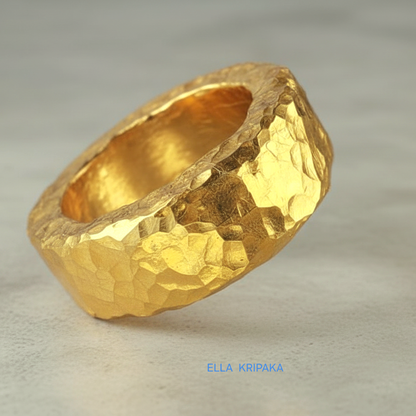 Hammered 24k 9999 Gold thick uneven ring organic with a textured gold surface on a grey concrete background, branded 'Ella Kripaka'