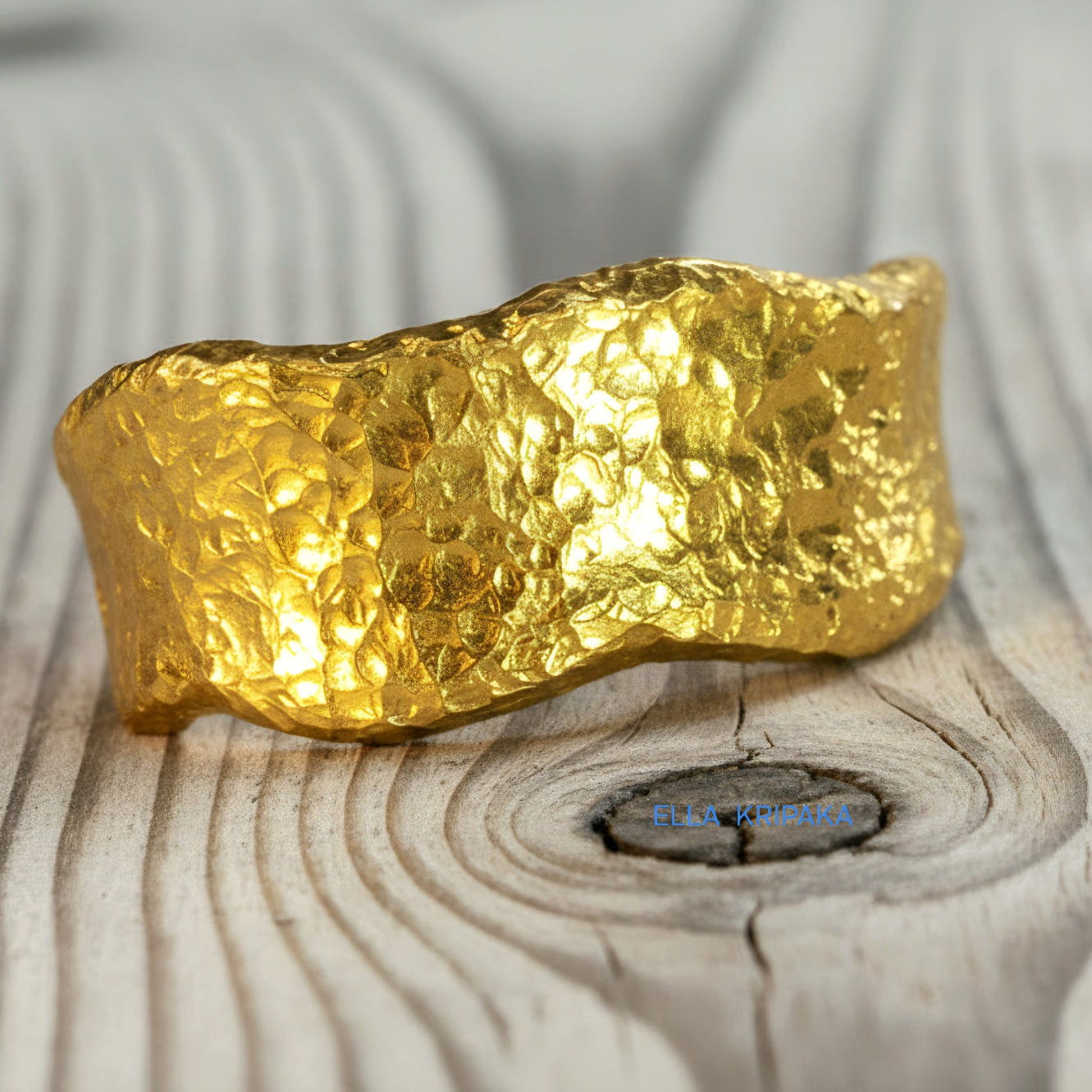 Hammered organic 24k Gold 9999 gold uneven wavy thick ring band with textured gold on a white old wooden background, branded 'Ella Kripaka'