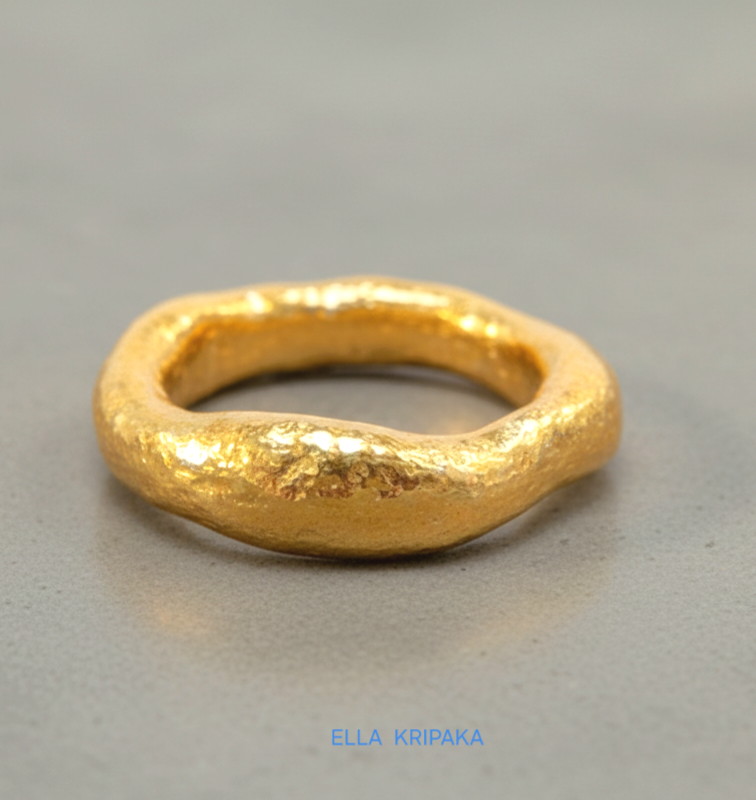 Hammered 24k 9999 Gold thick uneven ring organic with a textured gold surface on a grey concrete background, branded 'Ella Kripaka'