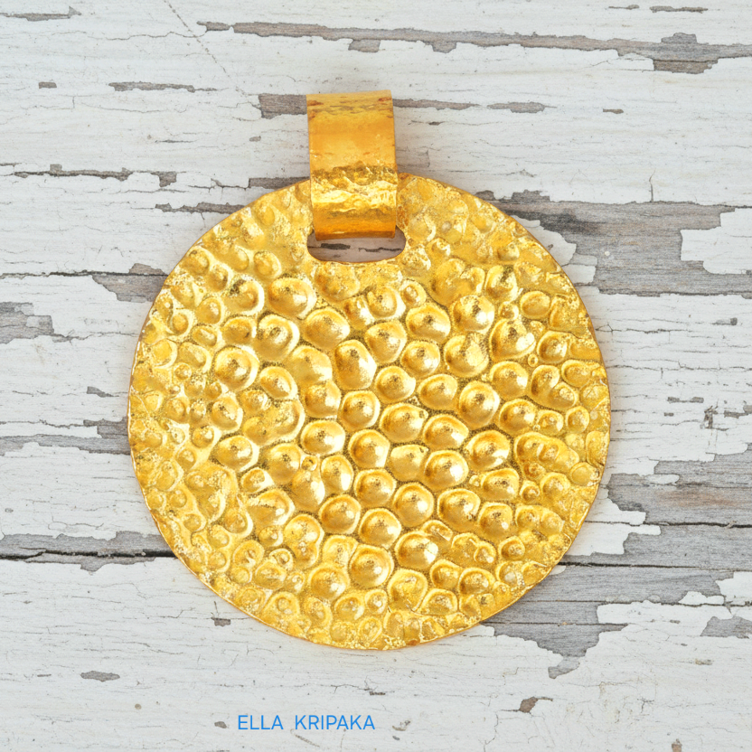 Organic hammered 24k gold, pure 9999 gold disk pendant with shiny forged gold textures on  white old wooden surface, artist-jeweler 'Ella Kripaka' branding