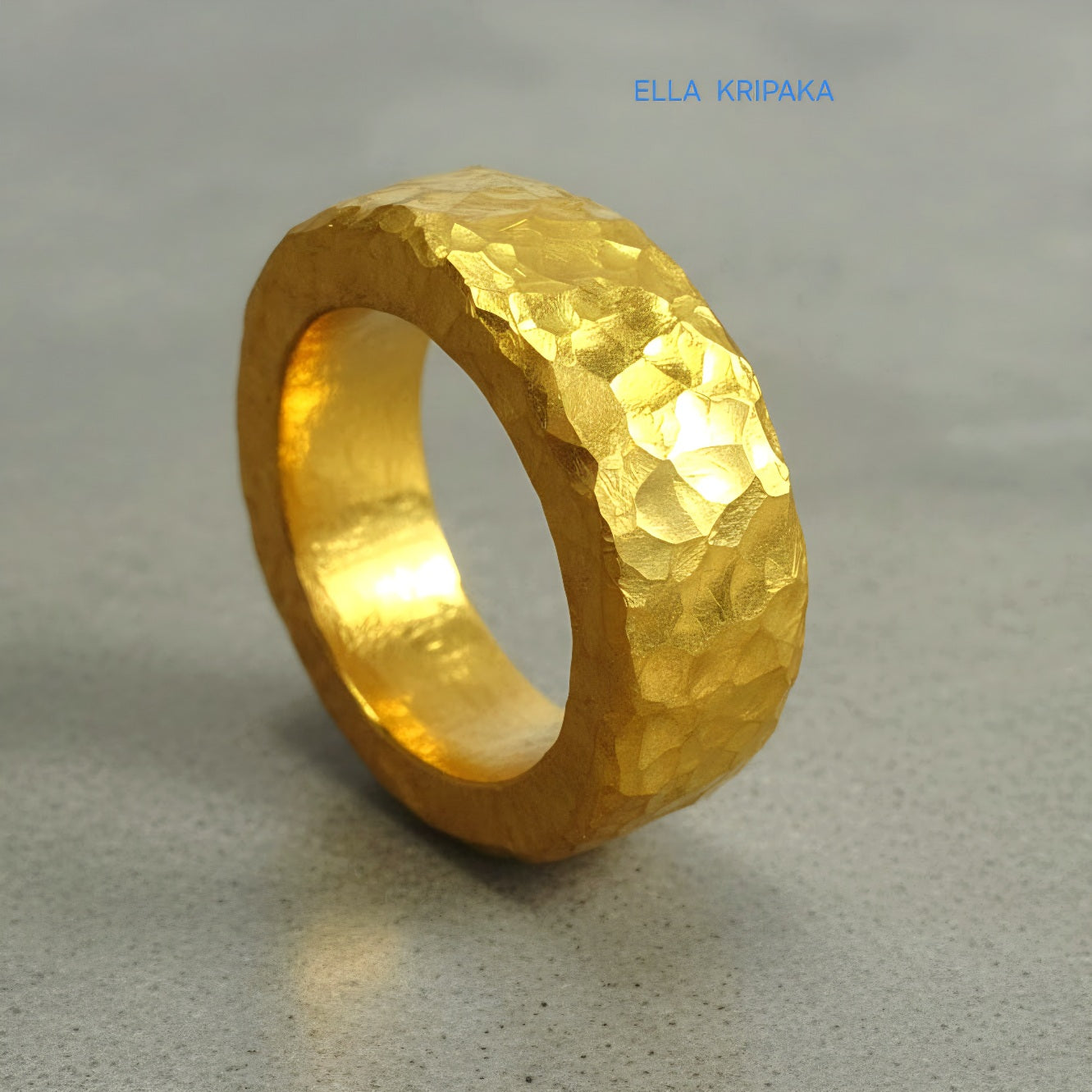 Hammered 24k 9999 Gold thick uneven ring organic with a textured gold surface on a grey concrete background, branded 'Ella Kripaka'