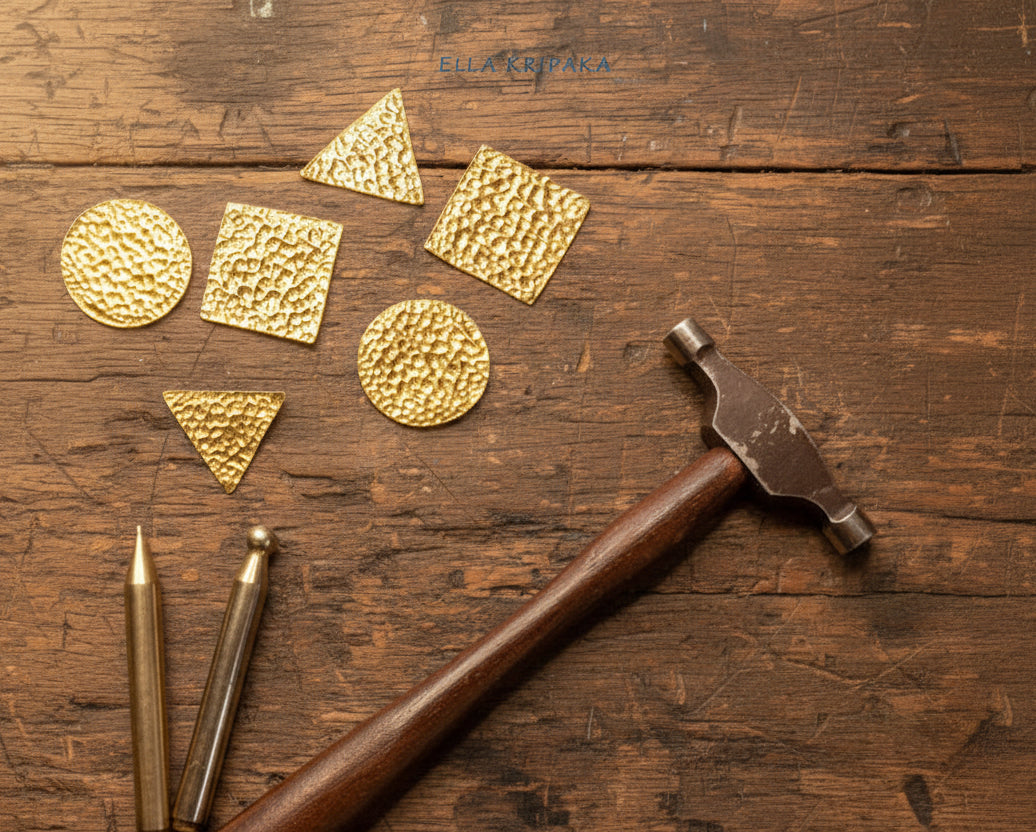 24k Gold hammered pieces with textured gold surface and jewelry tools on old wooden jewelry table with 'Ella Kripaka' branding