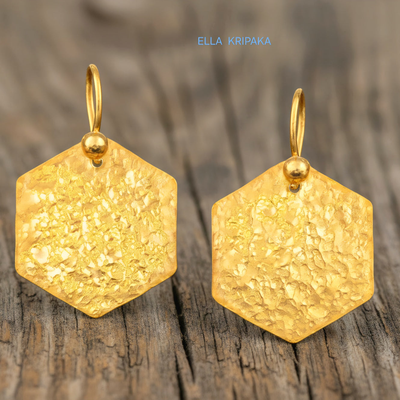 Hammered 24k gold, pure 9999 gold hexagon earrings with shiny forged gold textures on old wooden surface, artist-jeweler 'Ella Kripaka' branding