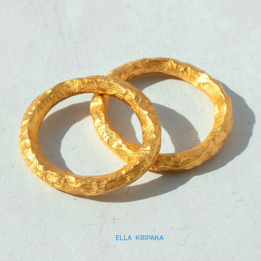 Twi organic 24k gold hammered rings with uneven textured surface on a white craft paper background, branded 'Ella Kripaka'