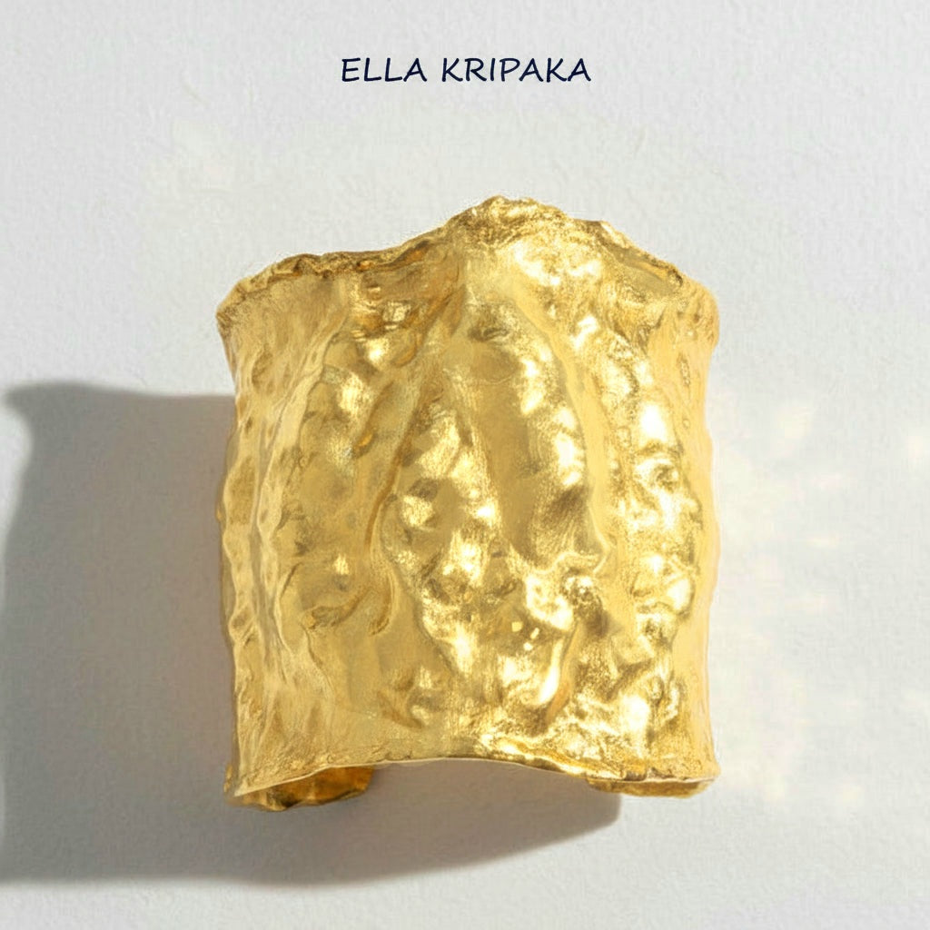 Hammered 24k gold large cuff bracelet with convex uneven textures on a white paper background, and with 'Ella Kripaka' branding