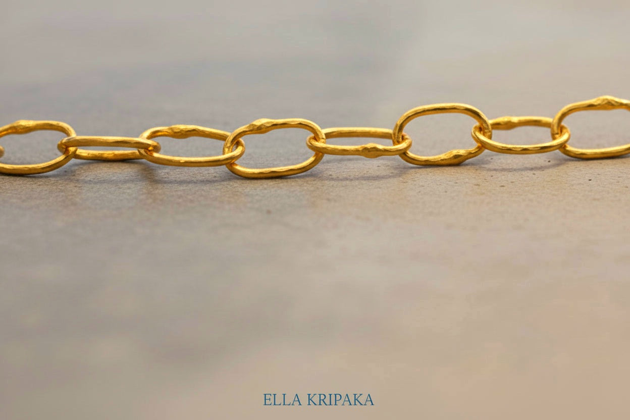 22k gold hammered chain necklace  on grey concrete background, artist-jeweler's name 'Ella Kripaka' branding