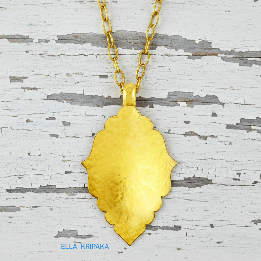 Hammered 24k gold Byzantine ornament pendant with thick chain on a white rustic wooden surface with 'Ella Kripaka' branding