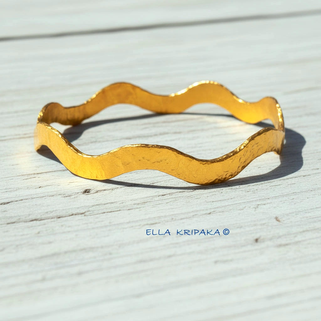 24k gold hammered bracelet thick bangle with wavy design on white rustic wooden background, branded 'Ella Kripaka'