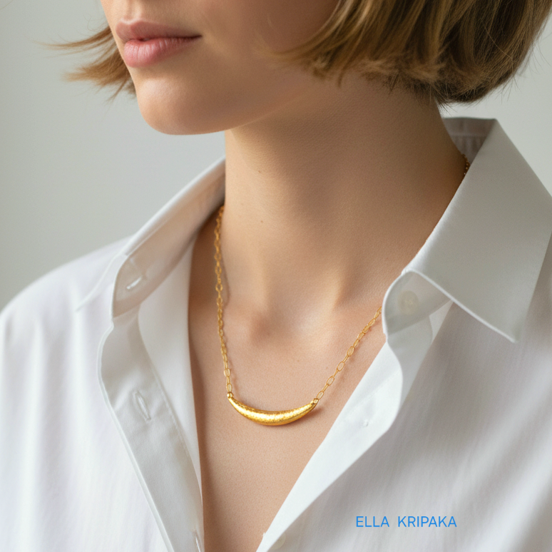 Hammered 24k gold convex Moon pendant with chain worn by a woman and with a white shirt background with 'Ella Kripaka' branding