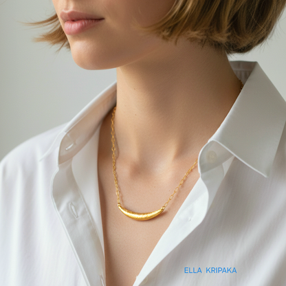 Hammered 24k gold convex Moon pendant with chain worn by a woman and with a white shirt background with 'Ella Kripaka' branding