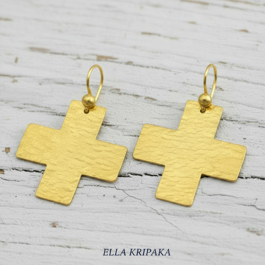 Hammered 24k Gold cross earrings on white old wooden background with 'Ella Kripaka' branding