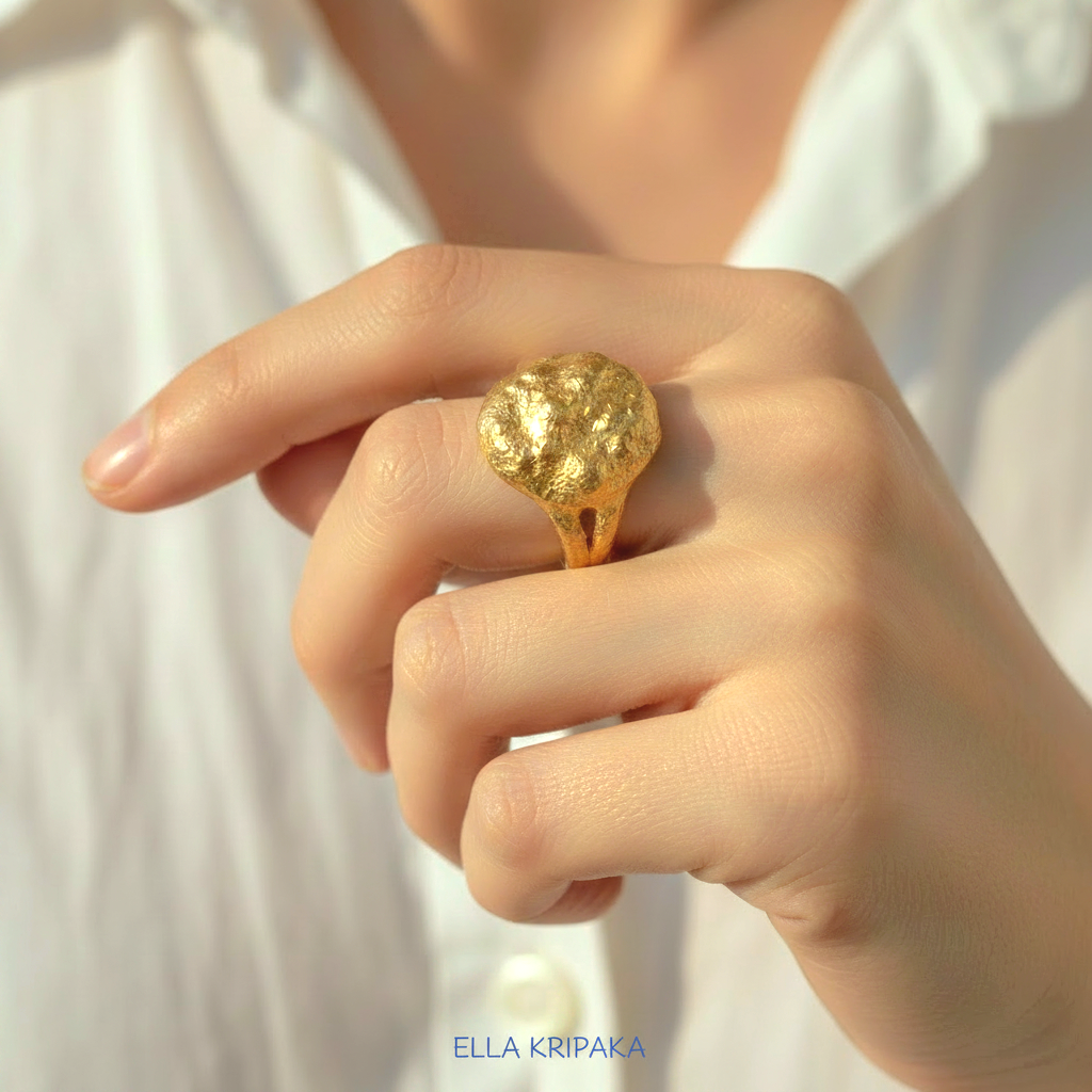Organic 24k gold convex signet with textured uneven design is worn by a woman on finger and on white shirt background, branded 'Ella Kripaka'